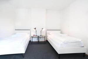 twee bedden in een kamer met witte muren bij Nest - Elsastrasse 16 in Zürich