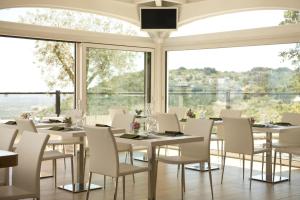 a restaurant with white tables and chairs and large windows at Al Mirador Resort in Selva di Fasano
