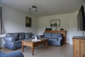 a living room with blue couches and a coffee table at Ottos Ferienhäuser in Rabenkirchen-Faulück