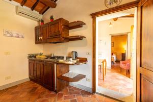 a kitchen with wooden cabinets and a counter top at Borgo Dolci Colline Resort Cipresso in Castiglion Fiorentino