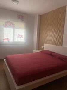 a bedroom with a red bed and a window at Apartamento Relualhu in Lloret de Mar