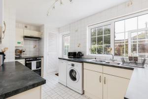 uma cozinha branca com um lavatório e uma máquina de lavar louça em Chimneys em Poole