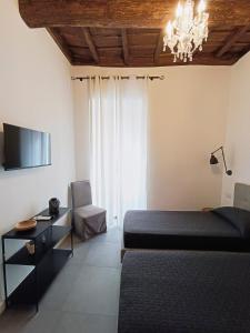 um quarto com 2 camas, uma televisão e um lustre em La tua casa a ViadelCorso em Roma