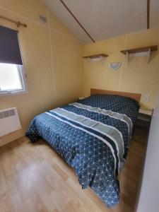 1 dormitorio con 1 cama con edredón azul y ventana en MH90 INCHELIN ST-ILLIERS, en Saint-Illiers-la-Ville