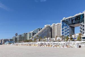 a beach with chairs and umbrellas and buildings at Super Spacious 3BR with Maid's Room in Five Palm in Dubai