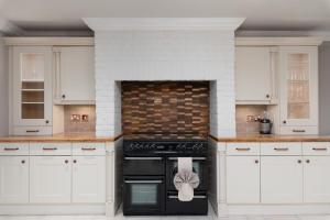 a kitchen with white cabinets and a black oven at Riversleigh 