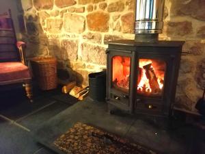 a fireplace in a stone room with a fire at Stable Lodge in Berwick-Upon-Tweed