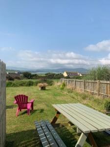 a picnic table and a red chair in a yard at Tig Monbretia in Dingle
