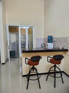 a kitchen with two bar stools and a counter at Villa Kayana Regency F9 Batu in Karangploso