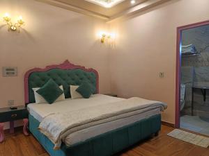 a bedroom with a large bed with a green headboard at Maya Hotel & Restaurant in Agra +14 photos