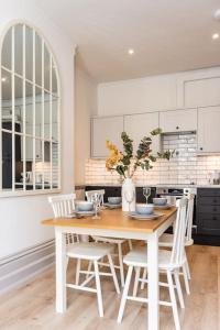 a white kitchen with a wooden table and chairs at 3 Castle Mews in Salisbury