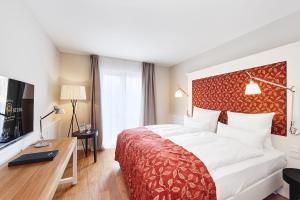 ein Hotelzimmer mit einem großen Bett und einem TV in der Unterkunft Berggasthof Königstuhl in Heidelberg