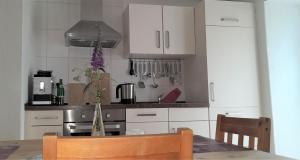a kitchen with white cabinets and a table with a vase at Ferienwohnungen "Zum Lochfeld" in Wittersheim +14 photos