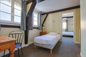 a small bedroom with a bed and a table and chairs at Hôtel François d'O in Caen