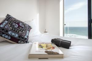 a book and a camera on a bed with the ocean at Fulmar in Torpoint