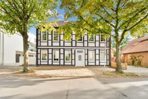 une maison noire et blanche avec des arbres devant elle dans l'établissement Schicke Monteurwohnung in Celle, à Celle