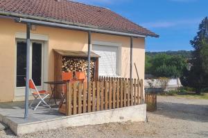 uma casa com uma cerca de madeira, uma mesa e cadeiras em Charmante petite maison em Torcenay