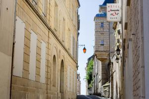 an alley with buildings and a tower in the distance at H&ocirc;tel Fran&ccedil;ois d'O in Caen