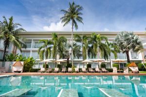 a pool with chairs and palm trees in front of a hotel at Chi Samui Resort in Bophut
