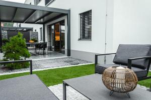 a house with a patio with a chair and a table at Apartma Vila Center LUX in Slovenj Gradec