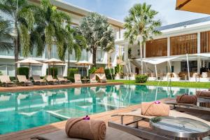 a pool at a resort with chairs and umbrellas at Chi Samui Resort in Bophut