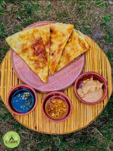 a slice of pizza on a plate with three dips at IL CAMPO Ecolodge & Boutique Hotel in Cairo
