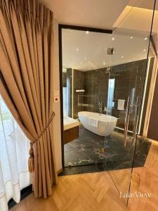 uma casa de banho com uma banheira e um grande chuveiro em vidro. em Executive Suite Apartment in Cape Coast - Lakeview by Agnes em Cape Coast