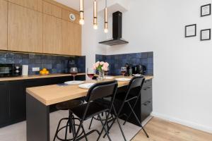 a kitchen with a wooden table and black chairs at Modern Apartment with Balcony by Renters in Gdańsk