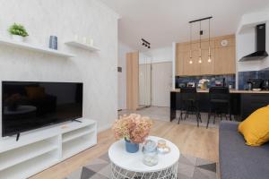 a living room with a large television and a kitchen at Modern Apartment with Balcony by Renters in Gdańsk