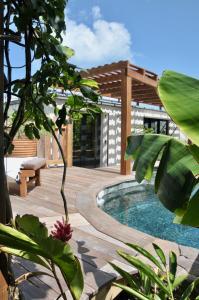 un patio trasero con piscina y terraza de madera en Case Canne a sucre, en Saint Barthelemy