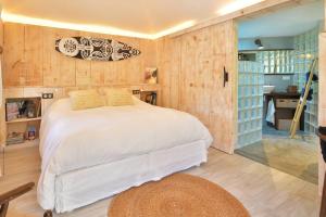 um quarto com uma cama branca num quarto com paredes de madeira em Case Canne a sucre em Saint Barthelemy