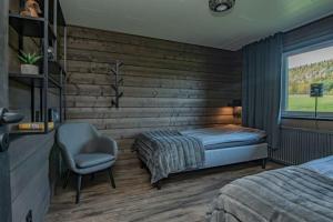 a bedroom with a bed and a chair and a window at Villa Black in Slussfors