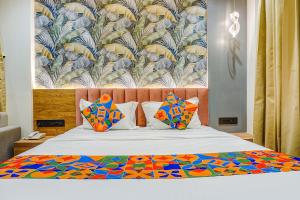 Cama con edredón y almohadas coloridos en FabHotel Prime Shourya Residency, en Pune