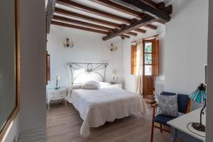 um quarto com uma cama branca e uma cadeira em El Jardín del Laurel em Candelario