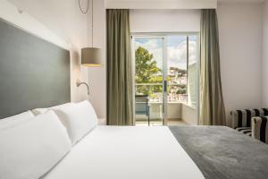 a bedroom with a white bed and a window at ARTIEM Audax - Adults Only in Cala Galdana