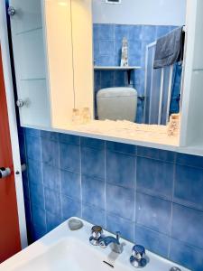 Appartamento Panorama في ريفا ديل غاردا: حمام من البلاط الأزرق مع حوض ومرآة
