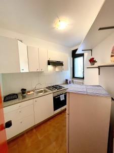 Appartamento Panorama في ريفا ديل غاردا: مطبخ بدولاب بيضاء وفرن علوي موقد