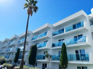 een wit gebouw met een palmboom ervoor bij Gran Santa Ponsa Apartments in Santa Ponsa