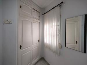 pasillo blanco con espejo y puerta en Pueblo Quinta en Benalmádena