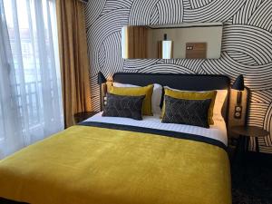 a bedroom with a yellow bed with a striped wall at Hotel Vacances Bleues Villa Modigliani in Paris