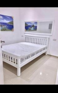 uma cama branca num quarto branco com duas pinturas em Sunny Garden. YBG. 1 Bedroom Apt. Quiet em Tel Aviv
