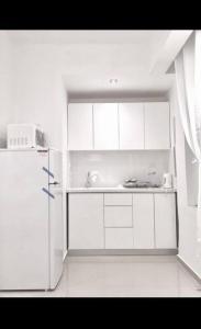 a kitchen with white cabinets and a refrigerator at Sunny Garden. YBG. 1 Bedroom Apt. Quiet in Tel Aviv