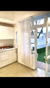 a kitchen with white cabinets and a large window at Sunny Garden. YBG. 1 Bedroom Apt. Quiet in Tel Aviv