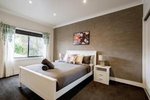 a bedroom with a white bed and a window at A Touch of Red - Spa, Theatre, Sleeps 6! in Waurn Ponds