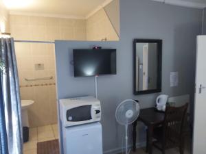 a bathroom with a tv on the wall and a table at Day Zha Voux Guesthouse in Potchefstroom