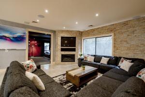 a living room with couches and a brick wall at A Touch of Red - Spa, Theatre, Sleeps 6! in Waurn Ponds