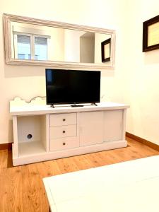 telewizor na białej szafce w salonie w obiekcie Recaredo Apartments w Sewilli