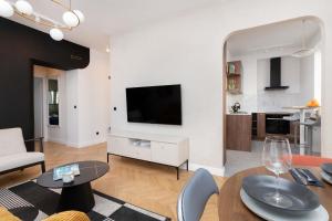 a living room with a television and a table and chairs at Apartment with Balcony Gdynia Downtown by Renters in Gdynia