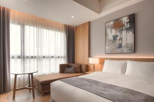 Grand Banyan Hotel في تاى نان: غرفه فندقيه بسرير وكرسي ونافذه