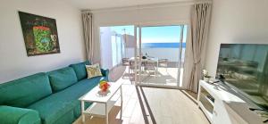 a living room with a green couch and a balcony at Ferienwohnung OCEAN SOUNDS 2 in Gran Tarajal